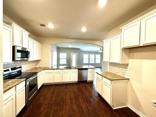 a large kitchen with stainless steel appliances a lot of counter space and wooden floor