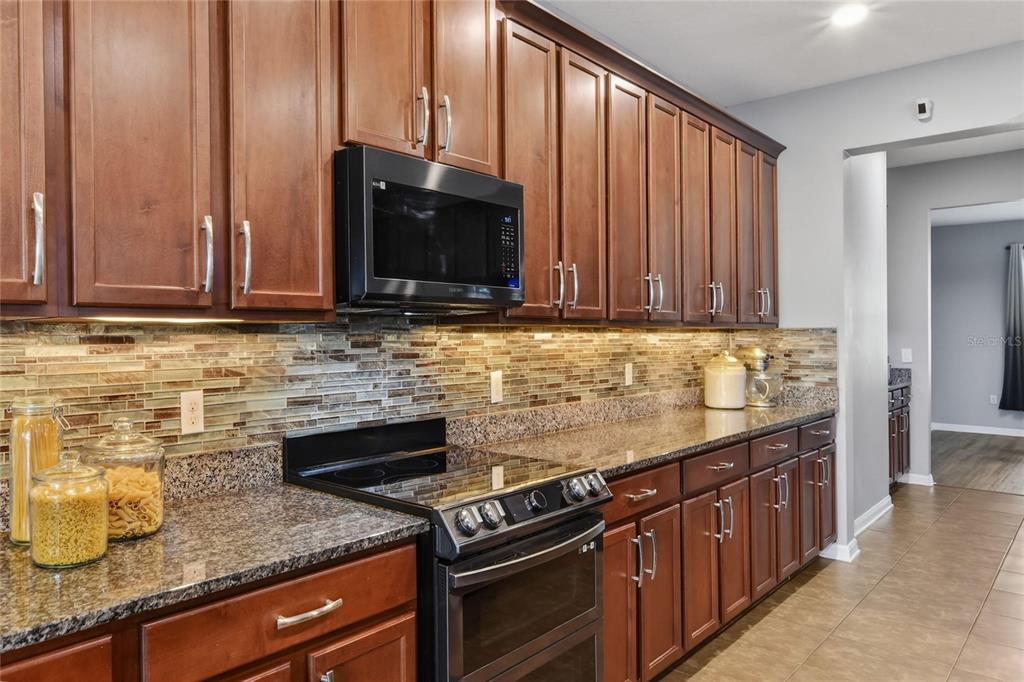232 Magneta Loop Auburndale, FL 33823 - Photo 38 of 80 a kitchen with granite countertop a stove top oven microwave and cabinets