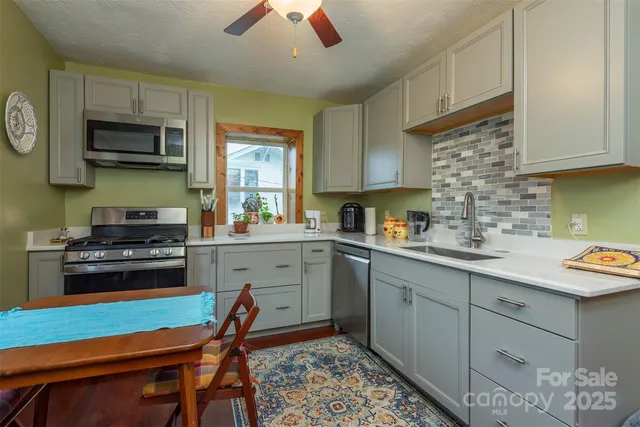 a kitchen with stainless steel appliances granite countertop a refrigerator a stove a sink dishwasher and a dining table with wooden floor