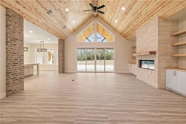 a view of an empty room with a window and kitchen view
