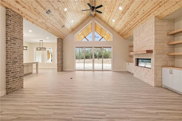 a view of an empty room with a window and kitchen view