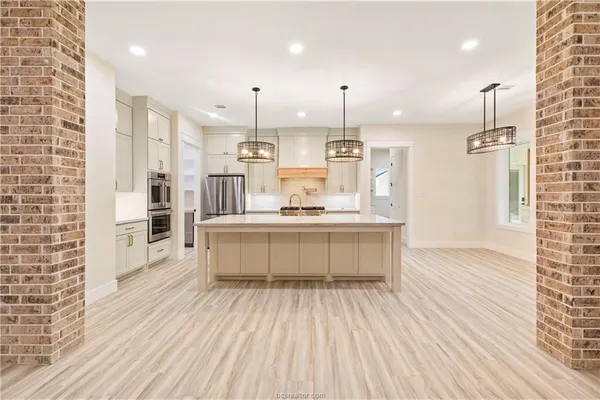 a large kitchen with kitchen island a sink stainless steel appliances and cabinets