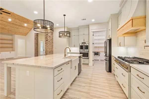 a large kitchen with stainless steel appliances kitchen island granite countertop a sink a stove and a refrigerator