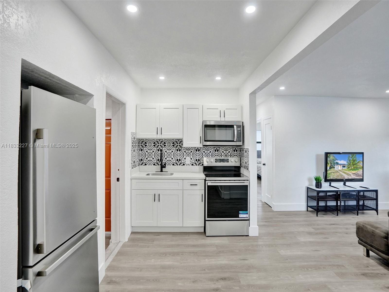 905 Southwest 22nd Street Fort Lauderdale, FL 33315 - Photo 9 of 25 a kitchen with stainless steel appliances a refrigerator stove and sink