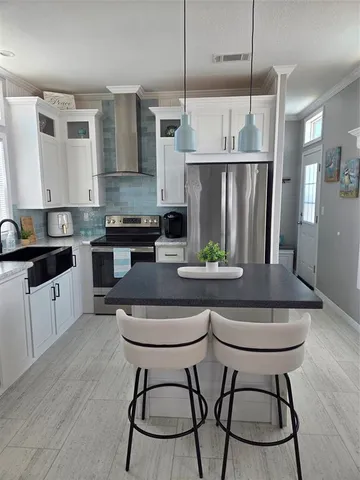 a kitchen with stainless steel appliances granite countertop a stove a sink a microwave a refrigerator and white cabinets