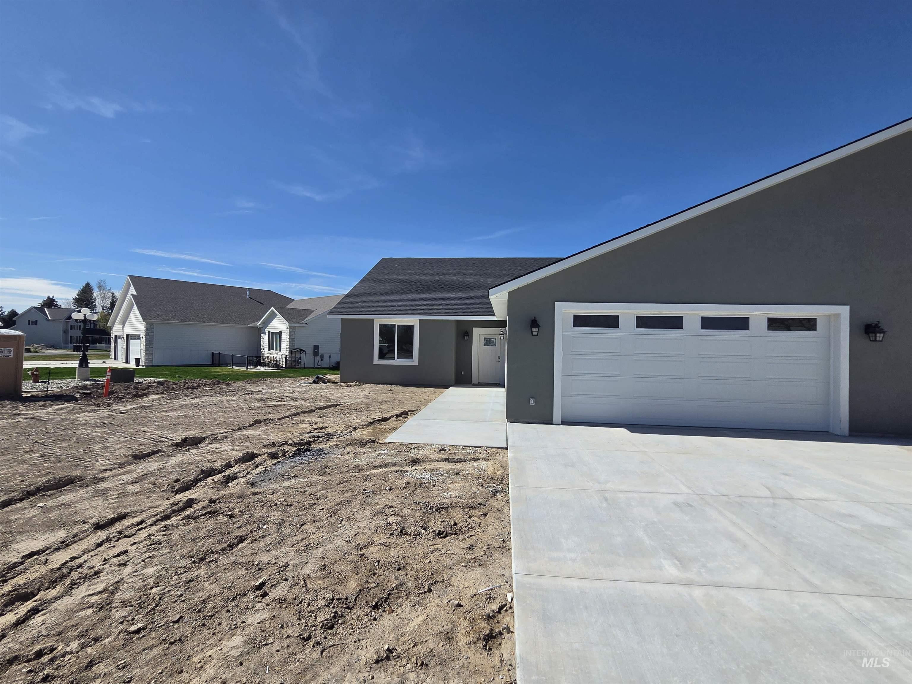 Ranch-style house with stucco siding, driveway, an attached garage, and a shingled roof