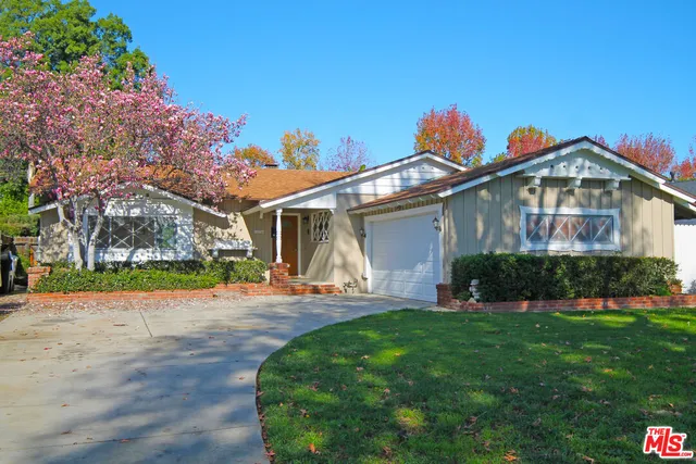 a front view of a house with a yard and potted plants