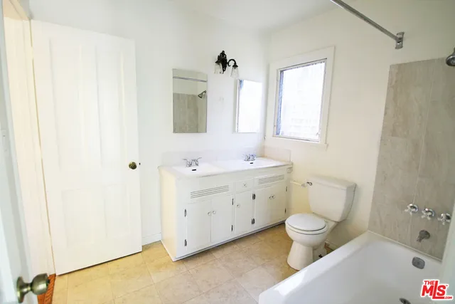 a bathroom with a double vanity sink toilet mirror and bathtub