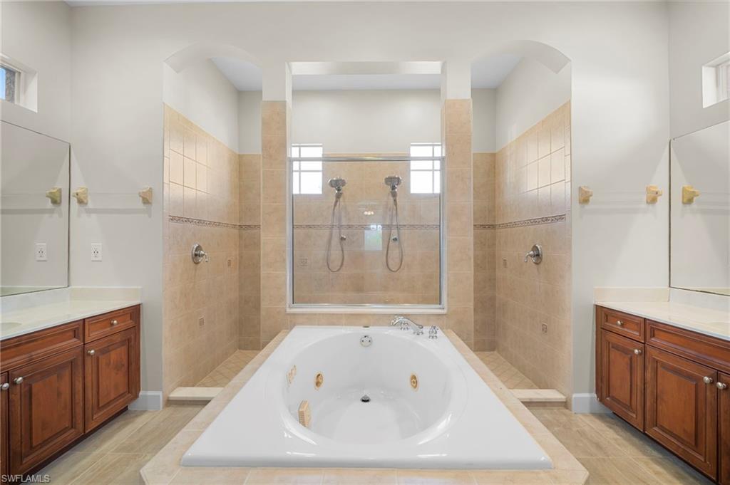 7915 Founders Circle Naples, FL 34104 - Photo 14 of 25 Full bath with vanity, a walk in shower, and a jetted tub