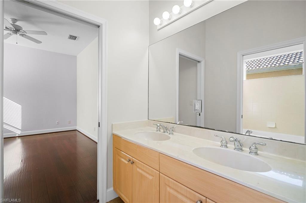 7915 Founders Circle Naples, FL 34104 - Photo 17 of 25 Full bathroom with double vanity, dark wood-style floors, healthy amount of natural light, and ceiling fan