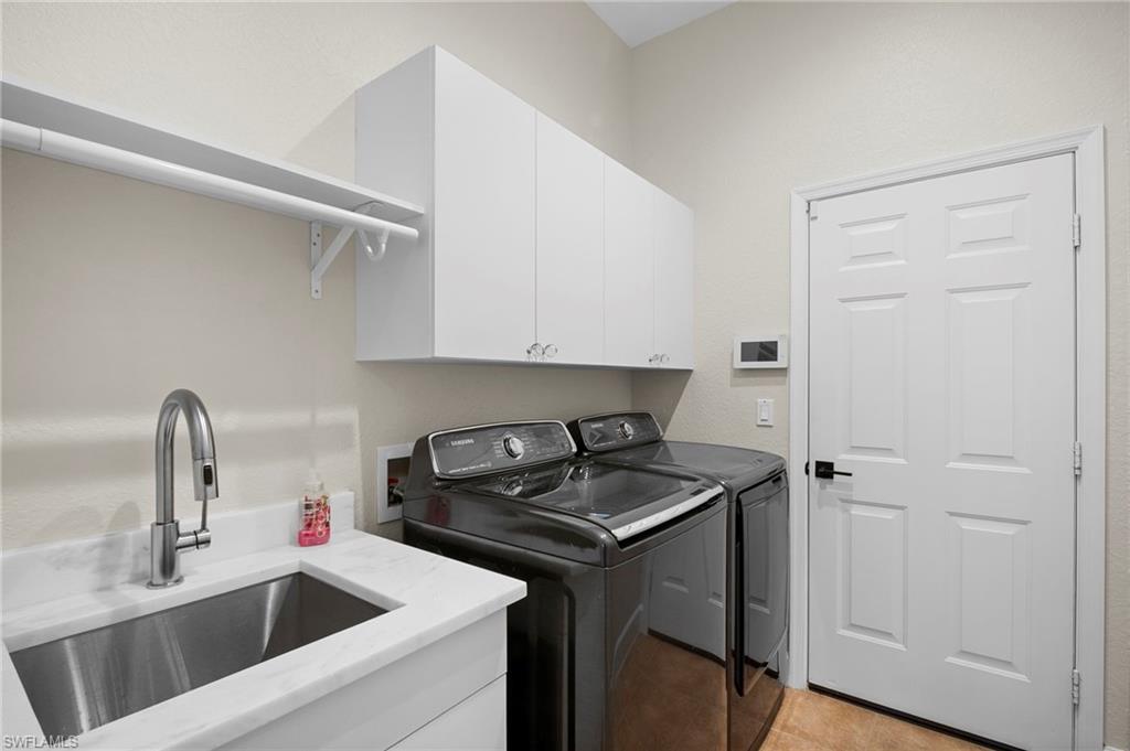 7915 Founders Circle Naples, FL 34104 - Photo 25 of 25 Washroom with cabinet space, washing machine and clothes dryer, light tile patterned floors, and a textured wall