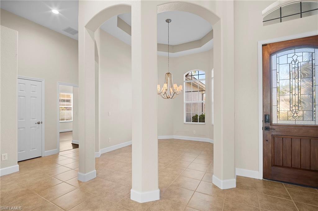 7915 Founders Circle Naples, FL 34104 - Photo 7 of 25 Entryway featuring healthy amount of natural light, a towering ceiling, a chandelier, light tile patterned floors, and arched walkways