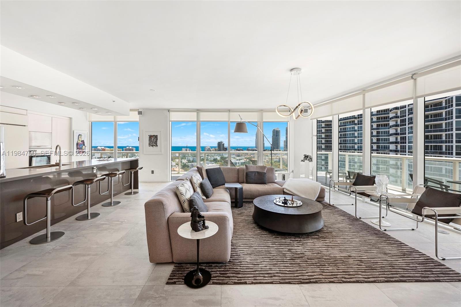 450 Alton Road, Unit 1507 Miami Beach, FL 33139 - Photo 17 of 72 a living room with white couches and a large window with kitchen view