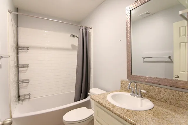 a bathroom with a granite countertop sink toilet and shower