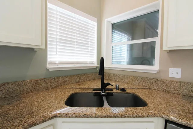 a bathroom with a granite countertop sink and window