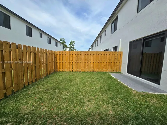 a view of backyard with tub and wooden fence