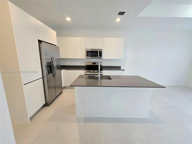 a living room with stainless steel appliances furniture a refrigerator and a counter top