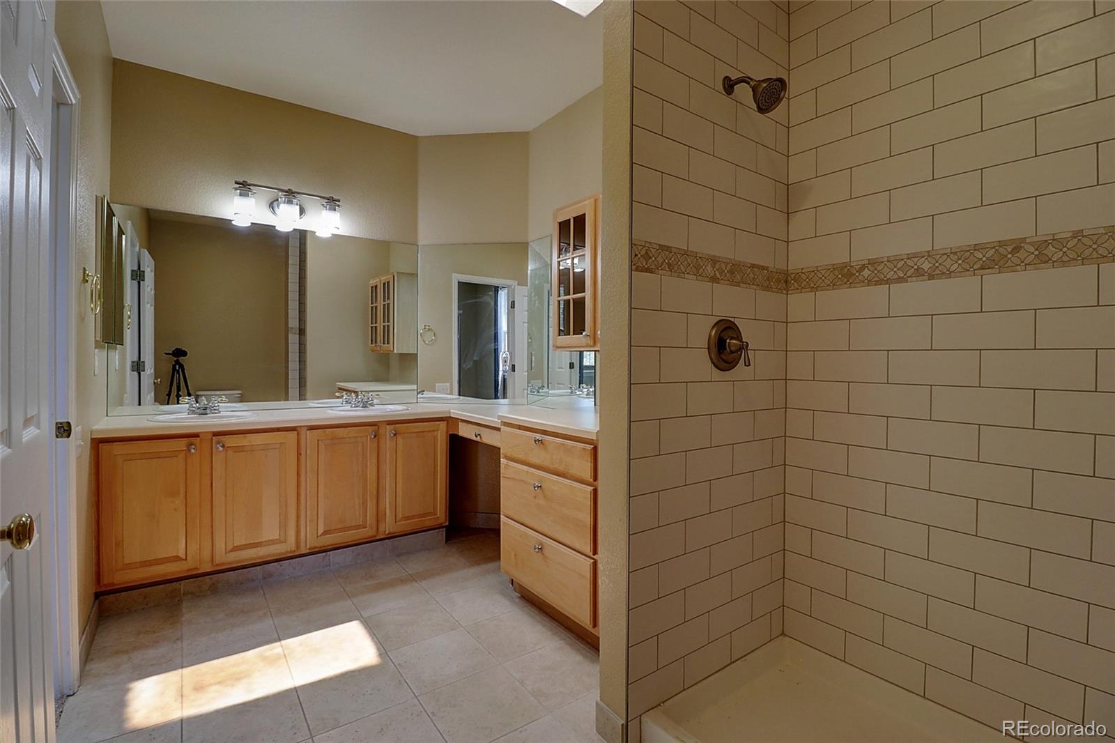 6203 Trailhead Road Highlands Ranch, CO 80130 - Photo 15 of 32 a bathroom with a double vanity sink a toilet a mirror and shower