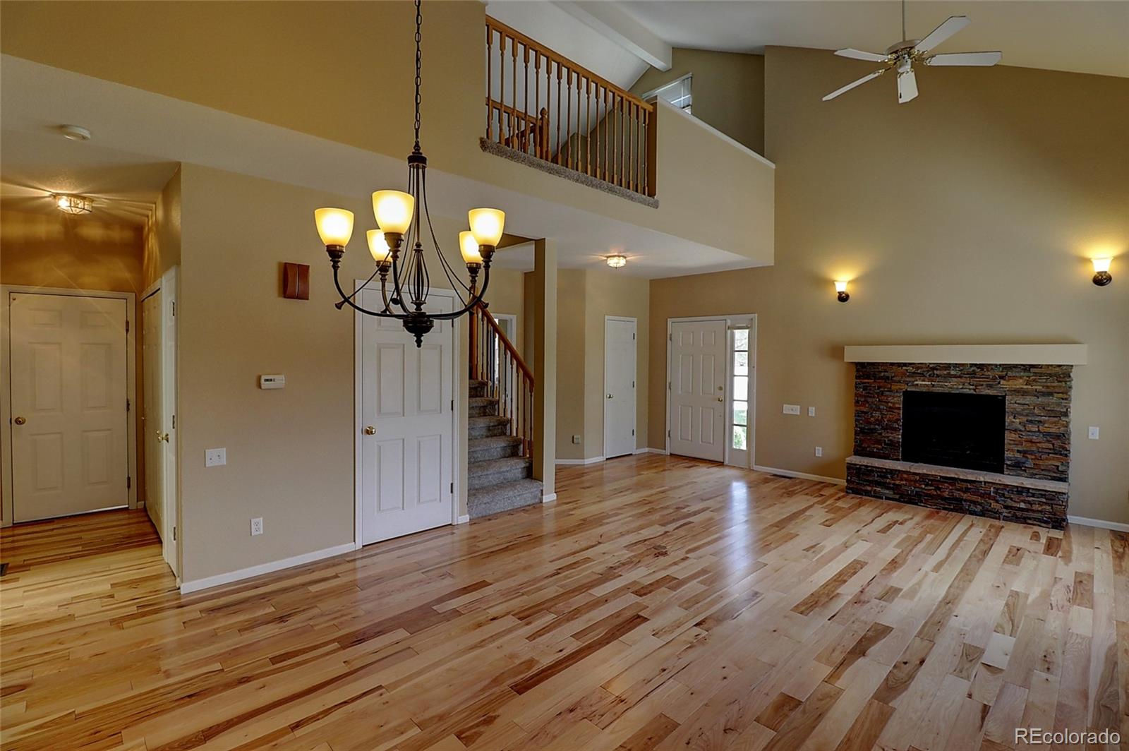 6203 Trailhead Road Highlands Ranch, CO 80130 - Photo 3 of 32 a view of a livingroom with wooden floor a ceiling fan and staircase