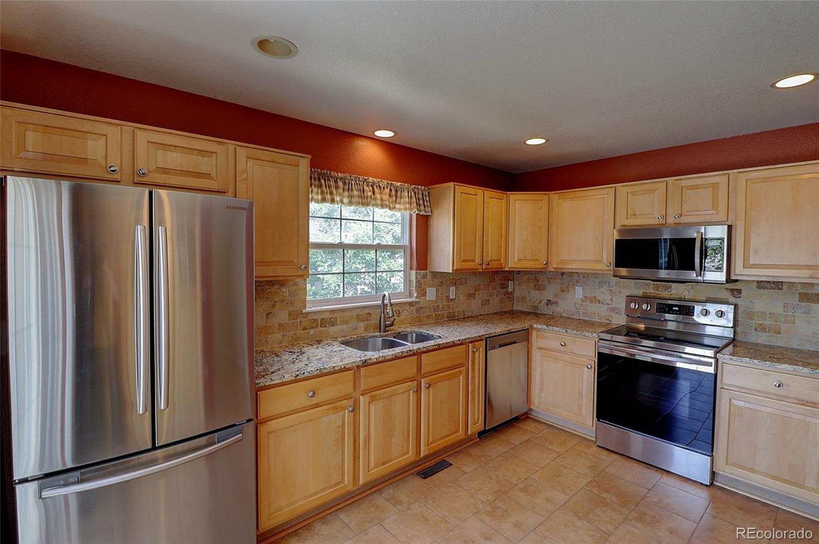 6203 Trailhead Road Highlands Ranch, CO 80130 - Photo 9 of 32 a kitchen with stainless steel appliances granite countertop a refrigerator a sink dishwasher a stove top oven a refrigerator with cabinets and wooden floor