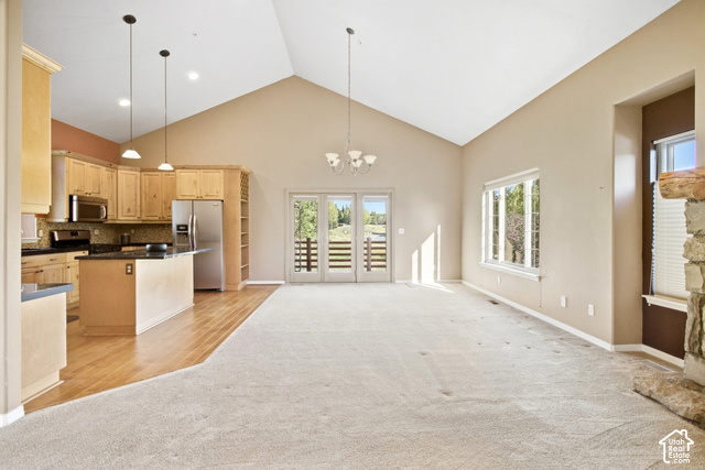 Vaulted ceilings, a stone fireplace, wood-finish flooring, and a kitchen featuring wood cabinetry and stainless steel appliances