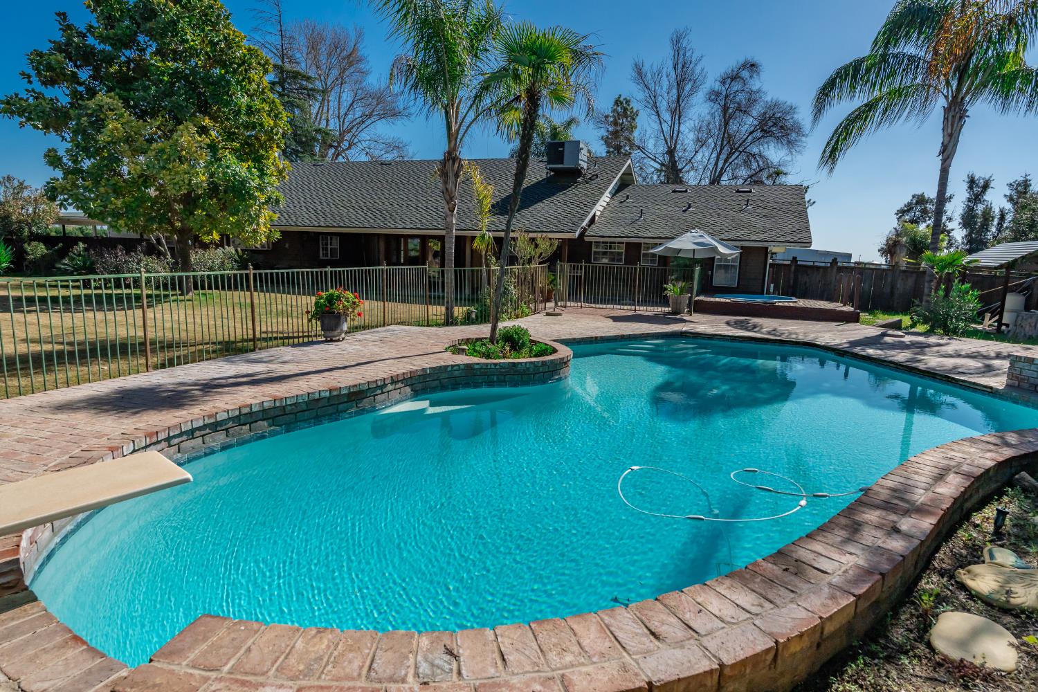 7176 East Butler Avenue Fresno, CA 93737 - Photo 5 of 76 a view of a swimming pool with a table and chairs under an umbrella