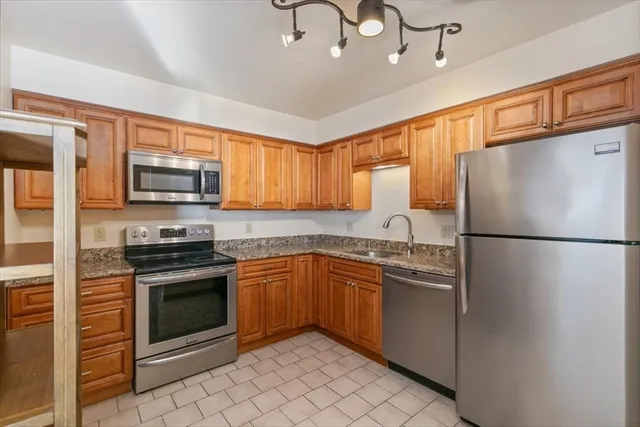 a kitchen with stainless steel appliances granite countertop a refrigerator stove a sink dishwasher and microwave