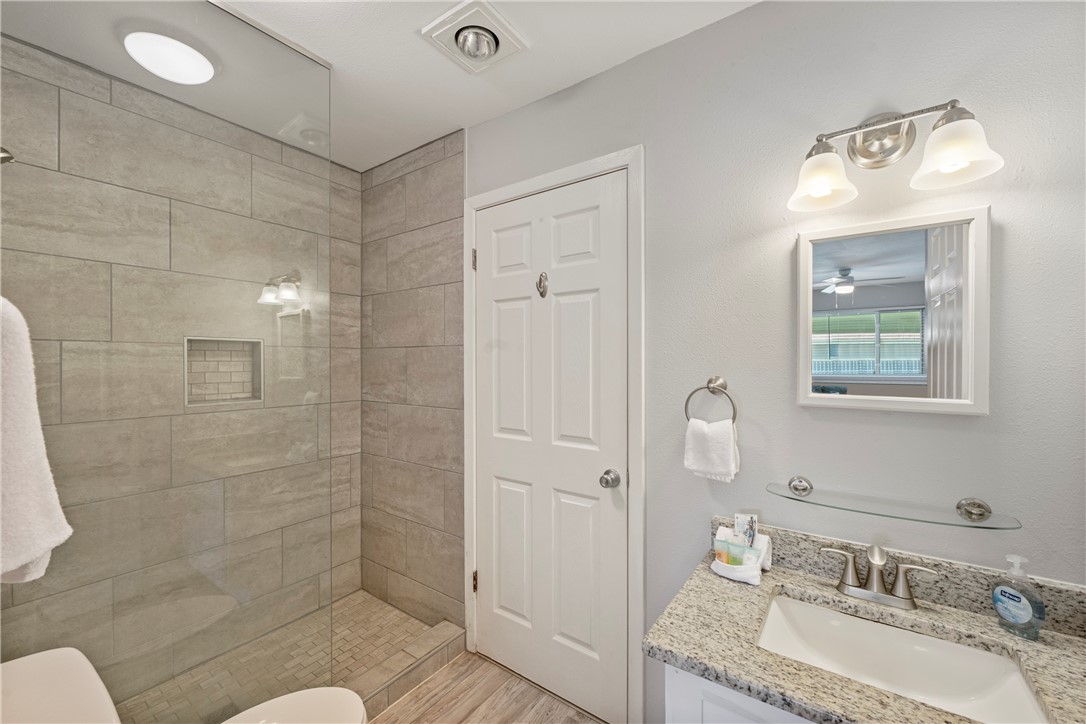 622 Beach Access Rd- 1a, Unit 231 Port Aransas, TX 78373 - Photo 11 of 24 a bathroom with a granite countertop sink toilet and shower