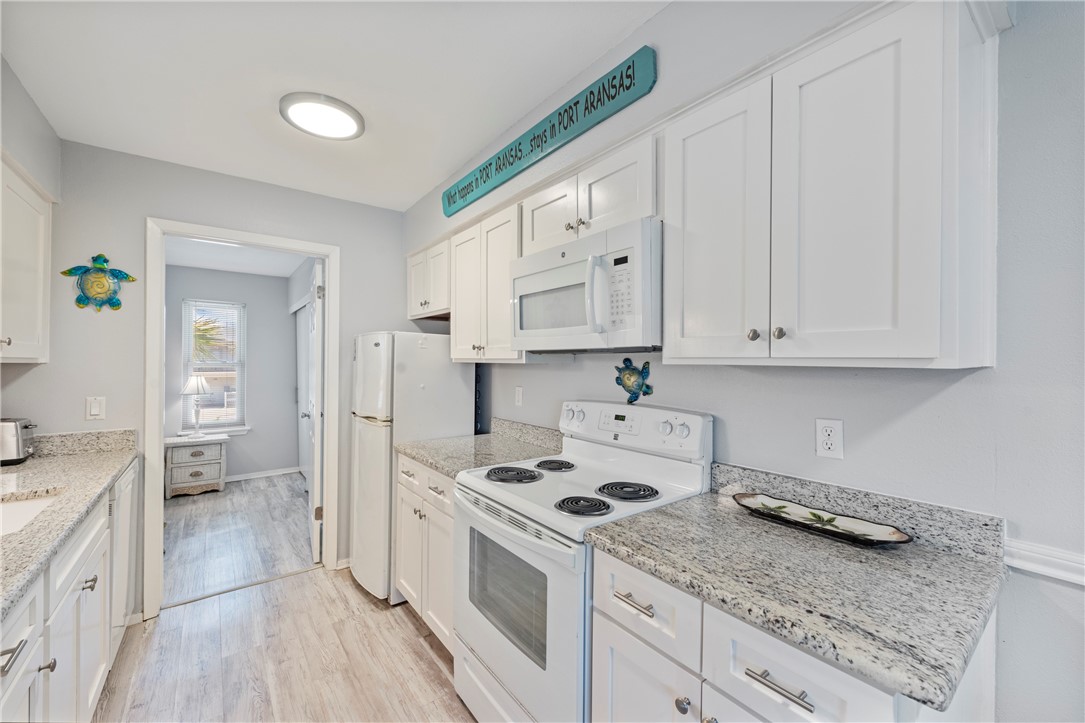 622 Beach Access Rd- 1a, Unit 231 Port Aransas, TX 78373 - Photo 6 of 24 a kitchen with granite countertop a sink a stove and cabinets