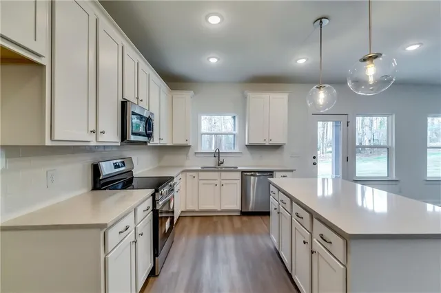 a kitchen with a sink stove cabinets and wooden floor