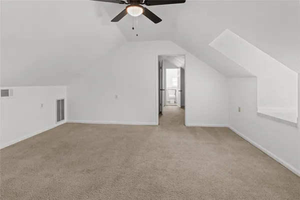an empty room with a ceiling fan and carpet