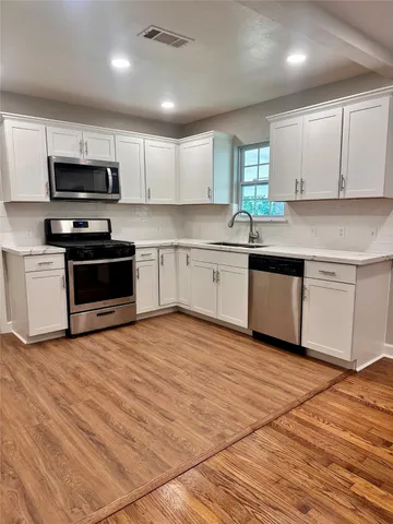 a kitchen with stainless steel appliances granite countertop a stove a sink and a microwave