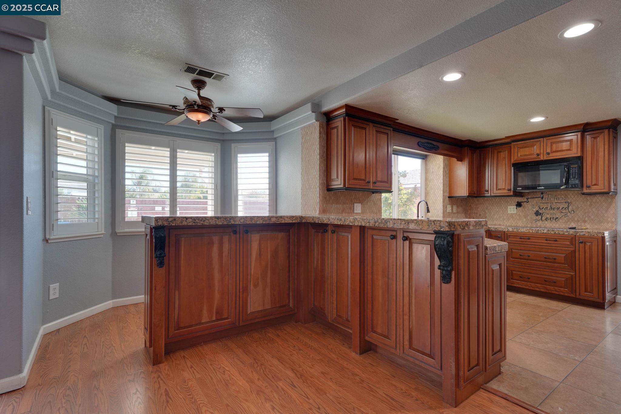 1210 Snow Ridge Court Modesto, CA 95351 - Photo 11 of 43 a kitchen with stainless steel appliances granite countertop a refrigerator a sink dishwasher a stove and a microwave oven on the wooden floor