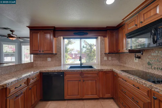 a kitchen with granite countertop wooden cabinets a sink and a stove