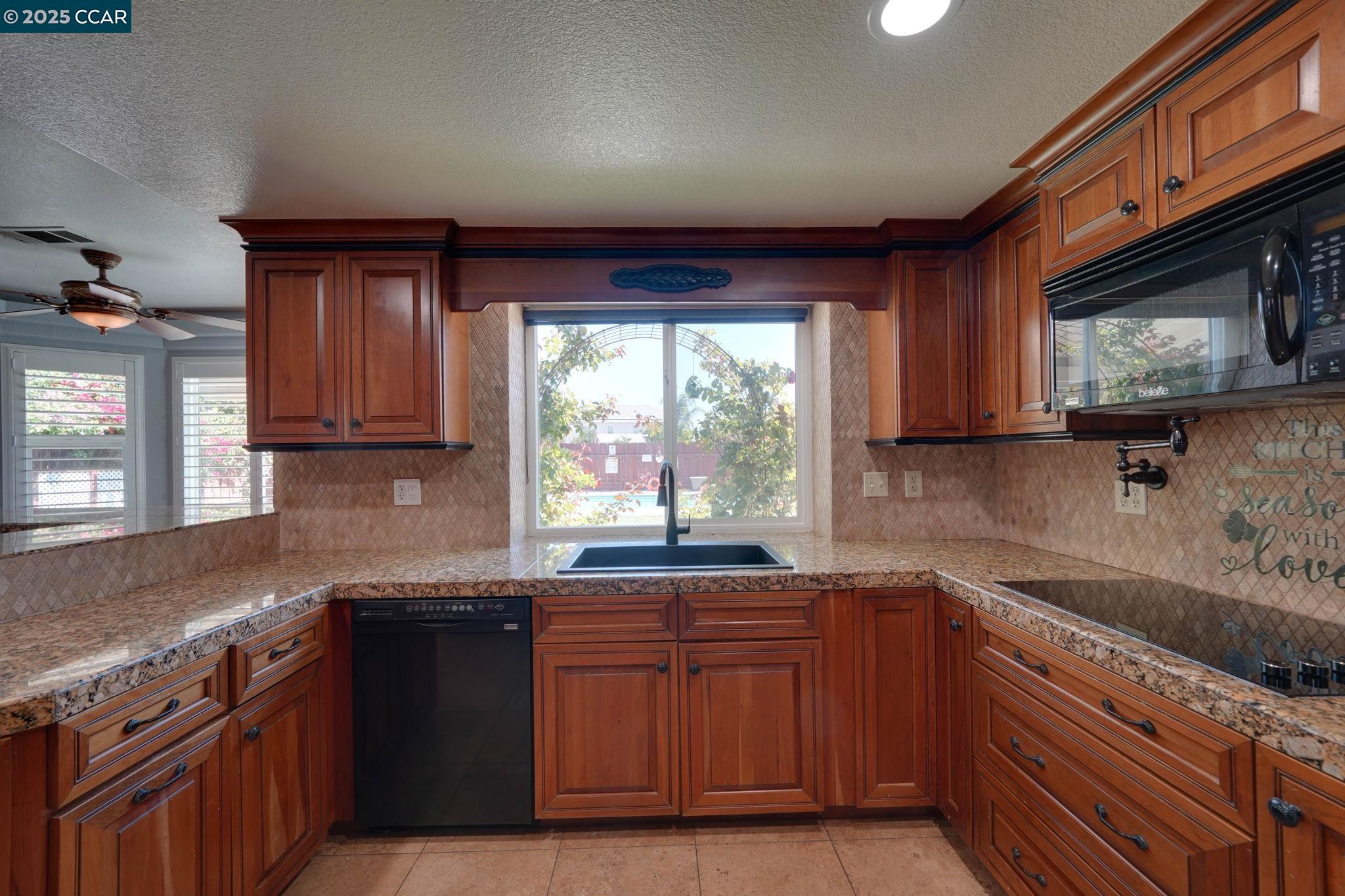1210 Snow Ridge Court Modesto, CA 95351 - Photo 16 of 43 a kitchen with granite countertop wooden cabinets a sink and a stove
