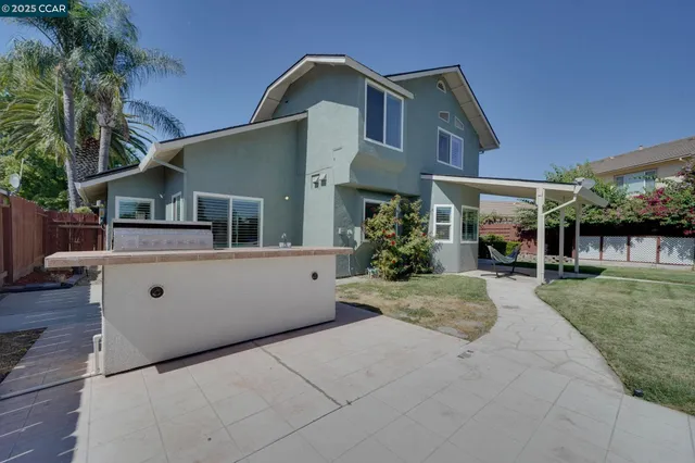 a view of a white house next to a yard with potted plants