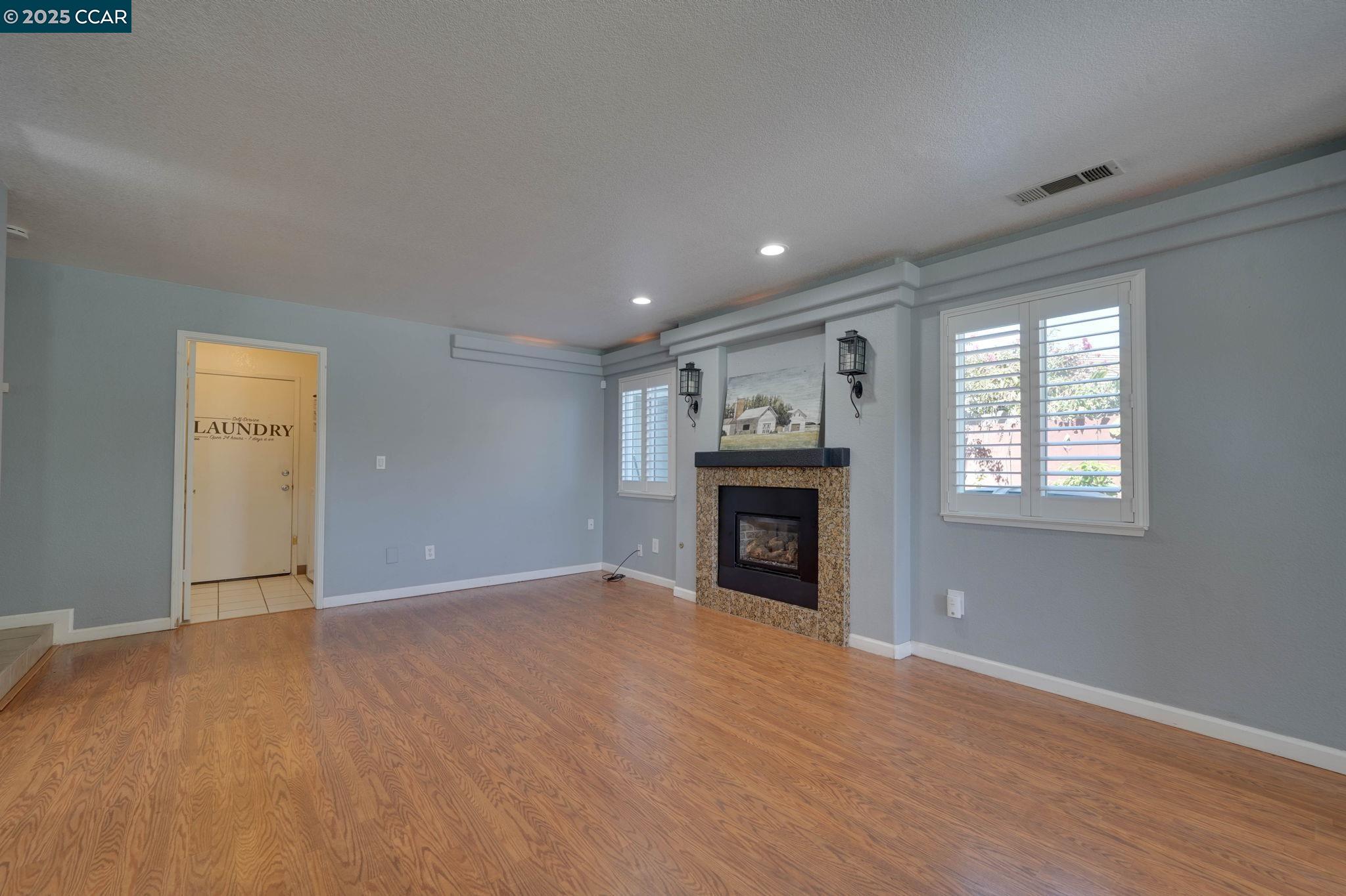 1210 Snow Ridge Court Modesto, CA 95351 - Photo 9 of 43 an empty room with wooden floor fireplace and windows