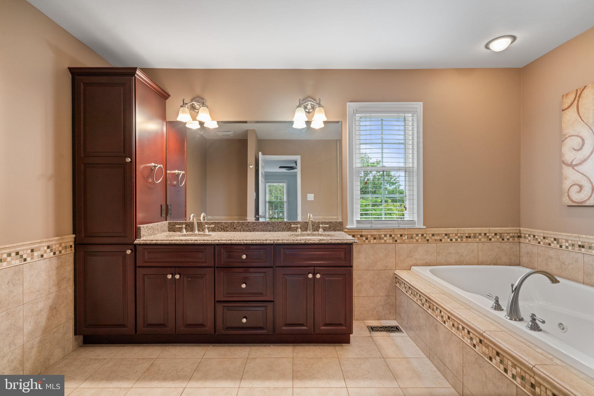 8527 Silverview Drive Lorton, VA 22079 - Photo 24 of 63 a bathroom with a granite countertop bathtub a sink and a large mirror