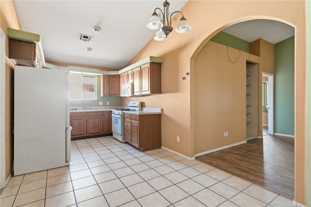 3740 North Kenneth Road Kingman, AZ 86409 - Photo 7 of 26 Kitchen featuring arched walkways, light tile patterned floors, white appliances, vaulted ceiling, and light countertops