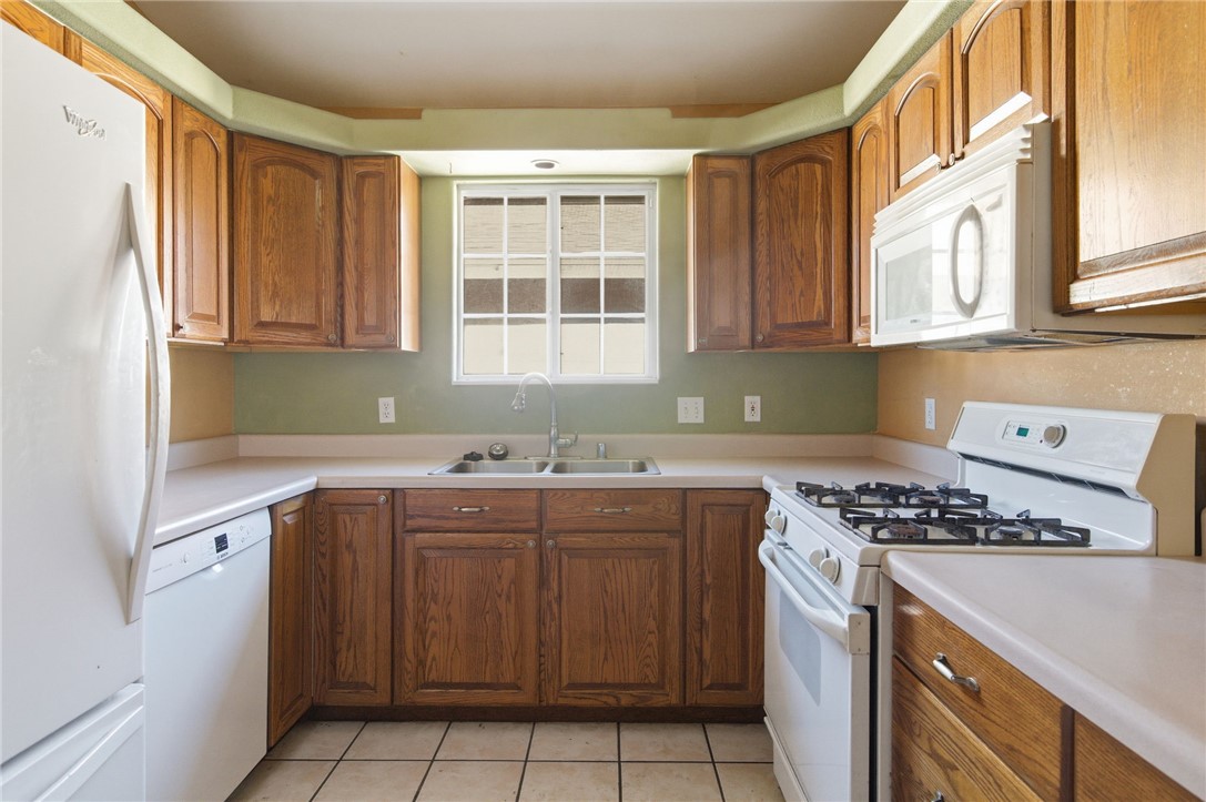 3740 North Kenneth Road Kingman, AZ 86409 - Photo 9 of 26 Kitchen featuring white appliances, light countertops, brown cabinetry, and light tile patterned flooring
