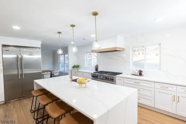 a kitchen with stainless steel appliances a stove a sink a center island and wooden floor