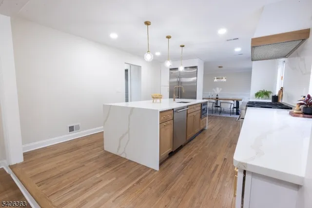 a large kitchen with stainless steel appliances a large counter top a sink a refrigerator and a fireplace