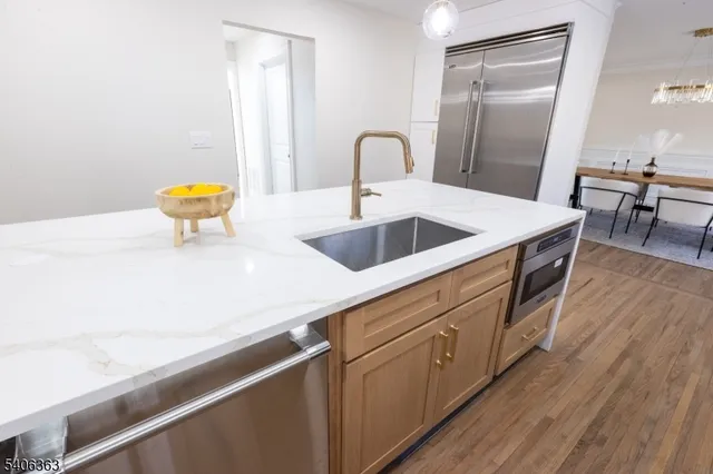 a kitchen with stainless steel appliances granite countertop a sink a stove and wooden floors