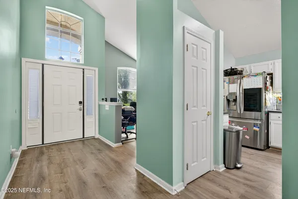 a view of a kitchen with a refrigerator wooden floor cabinet and a living room