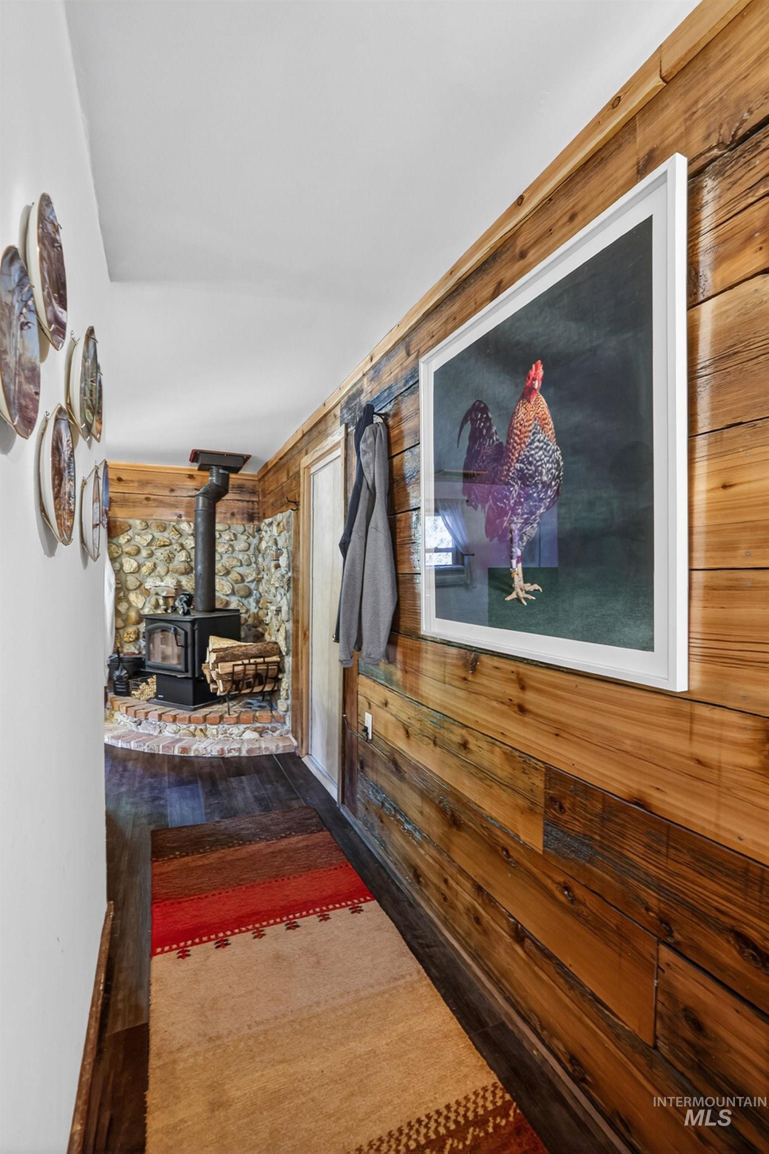 321 Secesh River Road McCall, ID 83638 - Photo 7 of 50 Hallway featuring rich wood-finish flooring, wood plank accent wall, and a stone accent wall with a built-in wood-burning stove