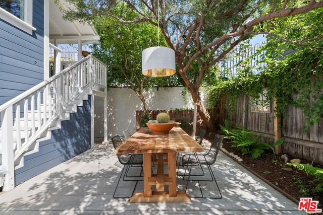 a view of a patio with table and chairs potted plants and large tree