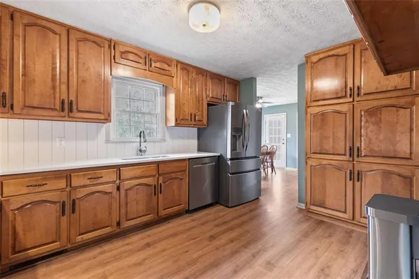 a kitchen with stainless steel appliances granite countertop a refrigerator a sink dishwasher and wooden cabinets with wooden floor