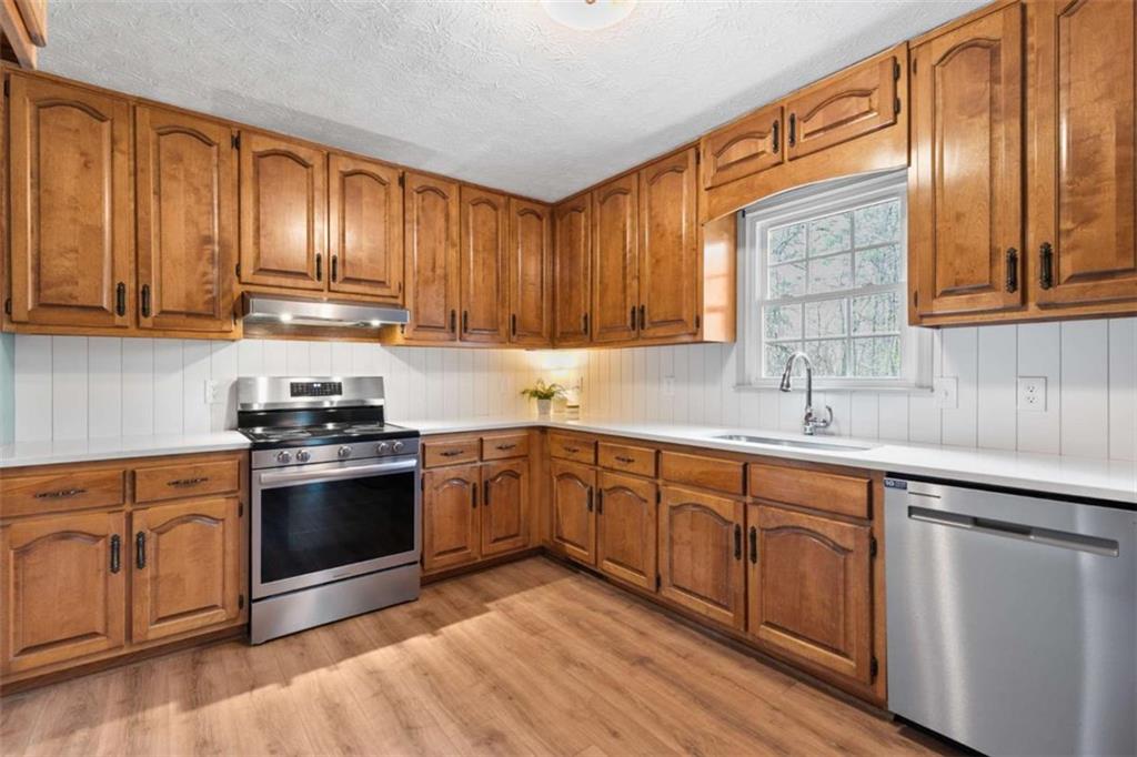138 Adams Road Fayetteville, GA 30214 - Photo 23 of 38 a kitchen with stainless steel appliances granite countertop a stove a sink dishwasher and a microwave oven with wooden floor