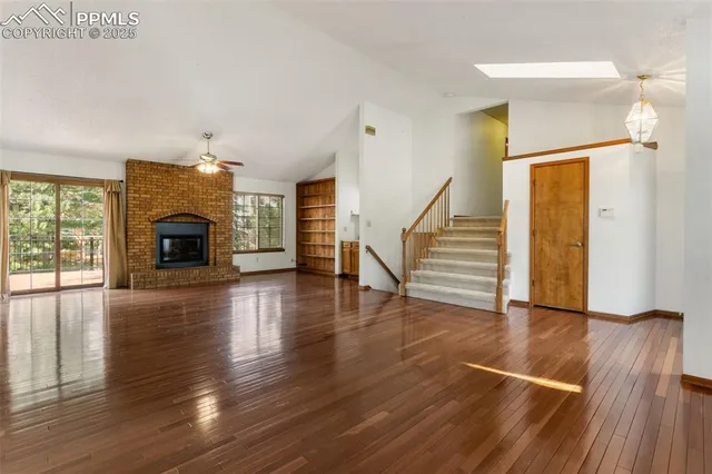 a view of a livingroom with wooden floor fireplace and staircase
