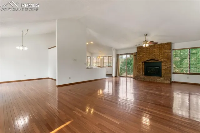 an empty room with wooden floor fireplace and windows